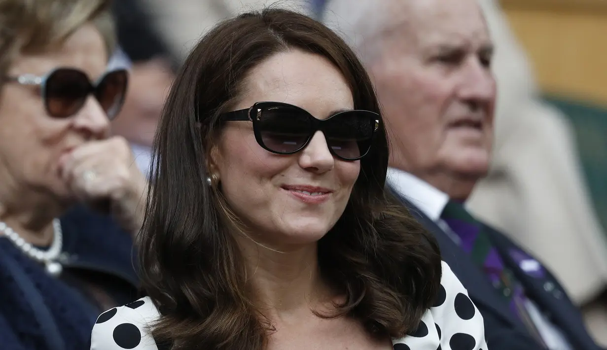 Kate Middleton saat menyaksikan pertandingan antara Andy Murray melawan Alexander Bublik pada babak pertama Wimbledon di London, Inggris (3/7). Kate Middleton tampil modis dengan dress polkadot dan kaca mata hitam. (AFP Photo/Adrian Dennis)