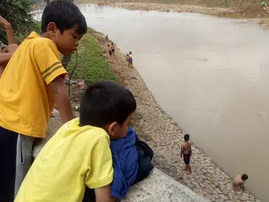 Anak-anak melihar teman-temannya  bermain di Bantaran sungai Kanal Banjir Barat, Tanah Abang, Jakarta, Sabtu (4/1/2020). Minimnya pengawasan  membuat anak-anak kerap bermain di tempat berbahaya yang berpotensi mengancam keselamatan mereka. (Liputan6.com/Angga Yuniar)