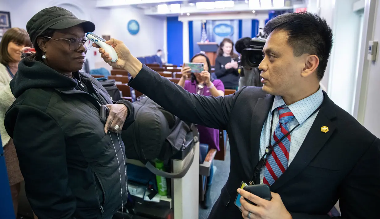 Seorang anggota media diambil suhunya oleh anggota kantor dokter Gedung Putih di Ruang Briefing James Brady di Washington, Minggu (15/3/2020). Di tengah kekhawatiran COVID-19, Gedung Putih memeriksa suhu tubuh setiap orang yang masuk, mulai dari pengunjung hingga wartawan. (AP/Alex Brandon)