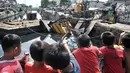 Anak-anak menyaksikan petugas mengevakuasi crane yang jatuh di kawasan Kemayoran, Jakarta, Kamis (6/12). Crane yang jatuh tersebut jatuh hingga menimpa rumah warga dan menyebabkan tiga orang luka-luka. (Merdeka.com/Iqbal S. Nugroho)