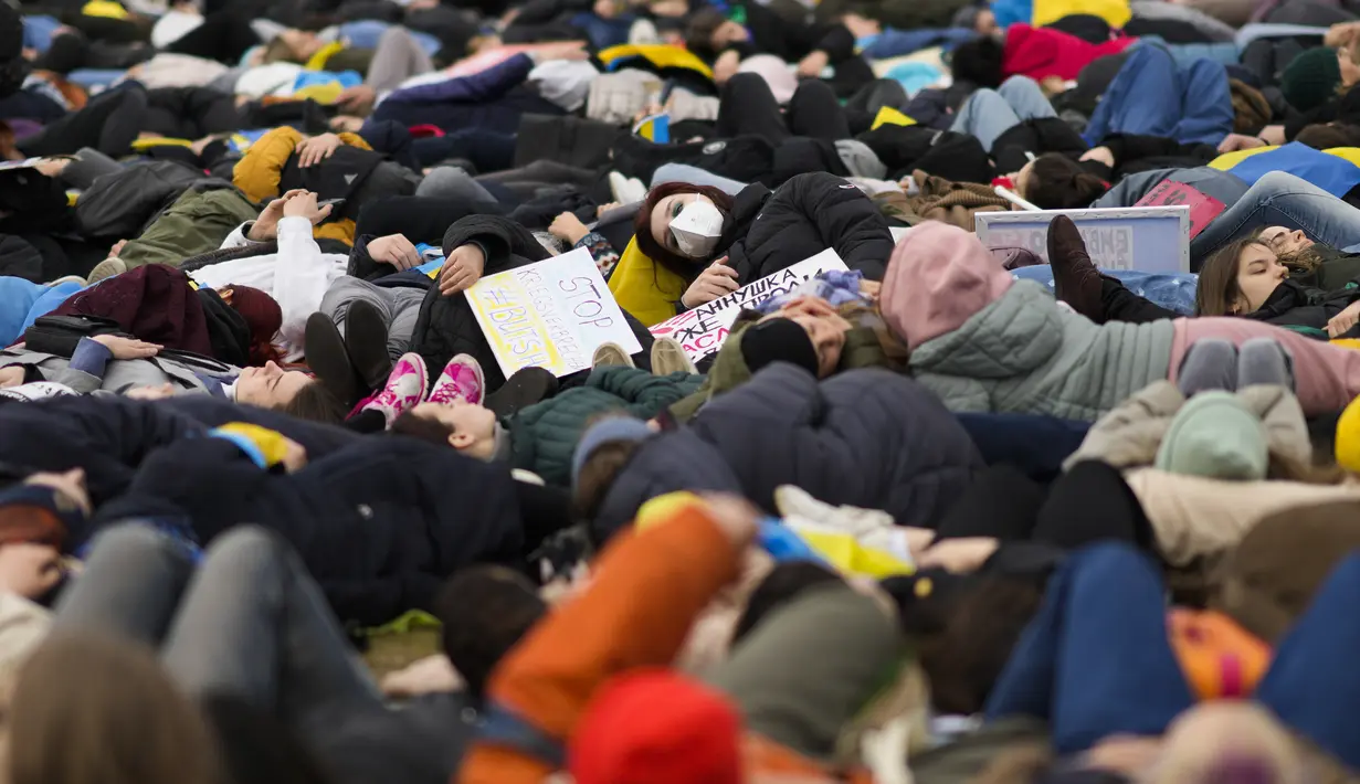 Orang-orang berbaring di tanah melambangkan mereka yang tewas dalam perang di Ukraina selama demonstrasi menentang invasi Rusia, dekat gedung parlemen Jerman, di Berlin, 6 April 2022. Pengunjuk rasa menuntut Berlin berhenti membeli minyak dan gas Rusia. (AP Photo/Markus Schreiber)