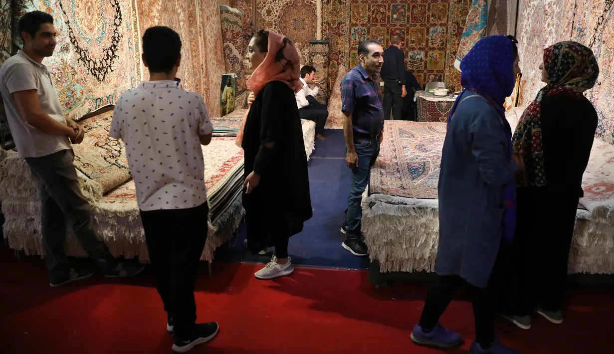 Pengunjung melihat-lihat karpet tenun yang dipamerkan dalam pameran di Teheran, Iran, Kamis (29/8/2019). Eksportir karpet Iran kehilangan pasar AS setelah Presiden Donald Trump menjatuhkan sanksi berat terhadap negara tersebut. (AP Photo/Vahid Salemi)