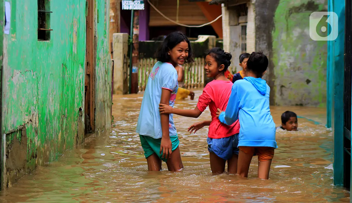 Anak-anak bermain banjir yang melanda kawasan Bidara Cina, Kecamatan Jatinegara, Jakarta Timur, Selasa (25/2/2020). Baru satu hari air surut, kawasan Bidara Cina yang bersebelahan dengan Kali Ciliwung kembali mengalami banjir. (merdeka.com/magang/ Muhammad Fayyadh)