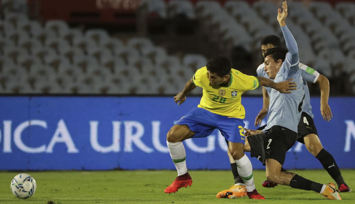 Penyerang Brasil, Roberto Firmino, berebut bola dengan bek Uruguay, Jose Maria Gimenez, pada laga lanjutan kualifikasi Piala Dunia zona CONMEBOL di Estadio Centenario, Rabu (18/11/2020) pagi WIB. Brasil menang 2-0 atas Uruguay. (AFP/Raul Martinez/pool)