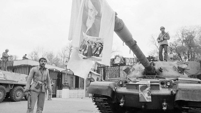 Gambar pemimpin spiritual Iran, Ayatollah Khomeini digantung pada laras tank di depan Istana Niavaran, Teheran, Iran, 13 Februari 1979. (AP Photo/Aristoteles Saris, File)