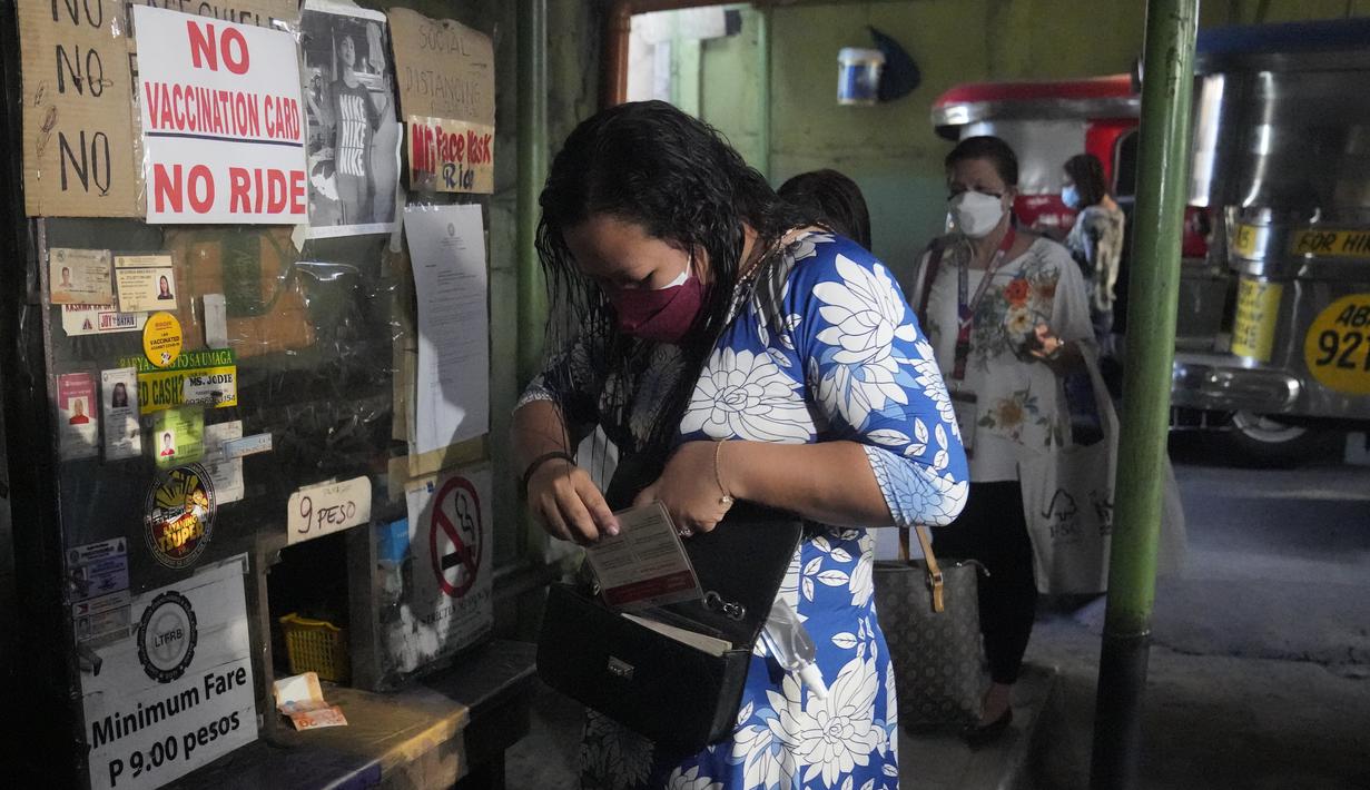 Seorang wanita memegang kartu vaksinasinya sebelum menaiki jip penumpang di sebuah terminal di kota Quezon, Senin (17/1/2022). Pemerintah Filipina melarang orang yang belum menerima vaksin COVID-19 untuk naik transportasi umum di ibu kota Manila mulai Senin ini. (AP Photo/Aaron Favila)