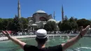 Seorang pemuda memberi isyarat saat menunggu di luar Hagia Sophia, Istanbul, Turki, Jumat (24/7/2020). Umat muslim melaksanakan salat Jumat pertama di Hagia Sophia dalam 86 tahun terakhir. (AP Photo/Yasin Akgul)