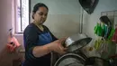 Ibu tunggal Tilda Kalaivani mencuci piring di apartemen sewaannya di Kuala Lumpur pada 6 Juli 2021. Ketika Malaysia memerangi pandemi corona yang memburuk, banyak keluarga berpenghasilan rendah yang berjuang dalam lockdown ketat mengibarkan bendera putih untuk memohon bantuan. (Mohd RASFAN/AFP)