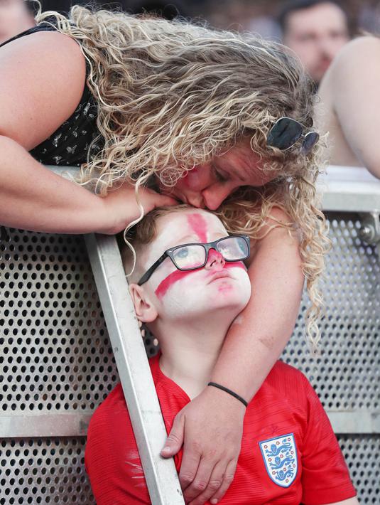 Seorang ibu mencium anaknya yang sedih usai timnas Inggris gagal melaju ke final Piala Dunia di Castlefield Bowl, Manchester, Rabu (11/7/2018). Kroasia menang 2-1 atas Inggris. (AP/Martin Rickett)