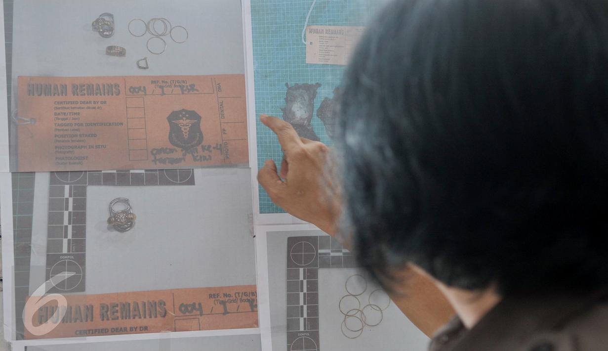 Petugas DVI Polri menunjukan foto properti hasil postmortem sekunder dari jenazah Korban KM Zahro di RS Polri, Jakarta, Selasa (3/1). (Liputan6.com/Yoppy Renato)