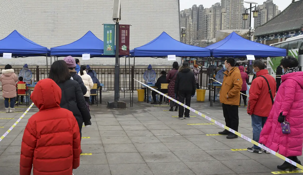 Warga mengenakan masker antre swab tes corona selama pengujian massal di Tianjin, China, Minggu (9/1/2022). Tianjin memulai pengujian massal terhadap 14 juta penduduknya setelah sekelompok anak-anak dan orang dewasa dinyatakan positif COVID-19, beberapa dengan varian omicron. (AP Photo/Andy Wong)