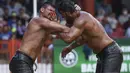 Pegulat Ismail Koc (kanan) dan Faruk Akkoyun bertanding di semifinal kejuaraan gulat minyak Kirkpinar tahunan ke-660, di Edirne, Turki barat laut, Minggu (11/7/2021). (AP Photo/Emrah Gurel)