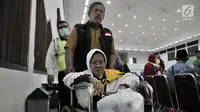 PPIH membantu salah seorang jemaah haji lansia dengan kursi roda saat tiba di Asrama Haji Pondok Gede, Jakarta, Rabu (29/8). (Merdeka.com/Iqbal S. Nugroho)