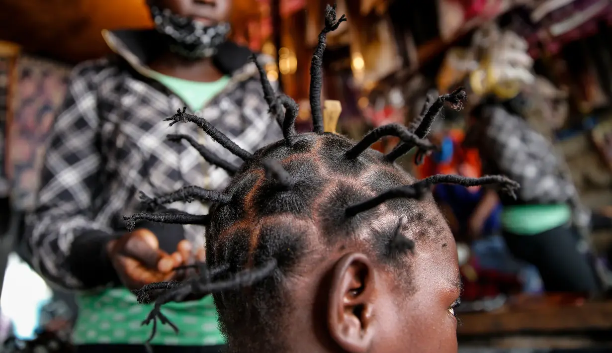 Gettrueth Ambio (12) rambutnya ditata dengan model yang terinsprasi dari corona Covid-19 oleh Mama Brayo Beauty Salon di daerah kumuh Kibera, Kenya, 3 Mei 2020. Corona telah menghidupkan kembali gaya rambut di Afrika Timur yang memiliki lonjakan kepang bentuk khas virus. (AP/Brian Inganga, File)