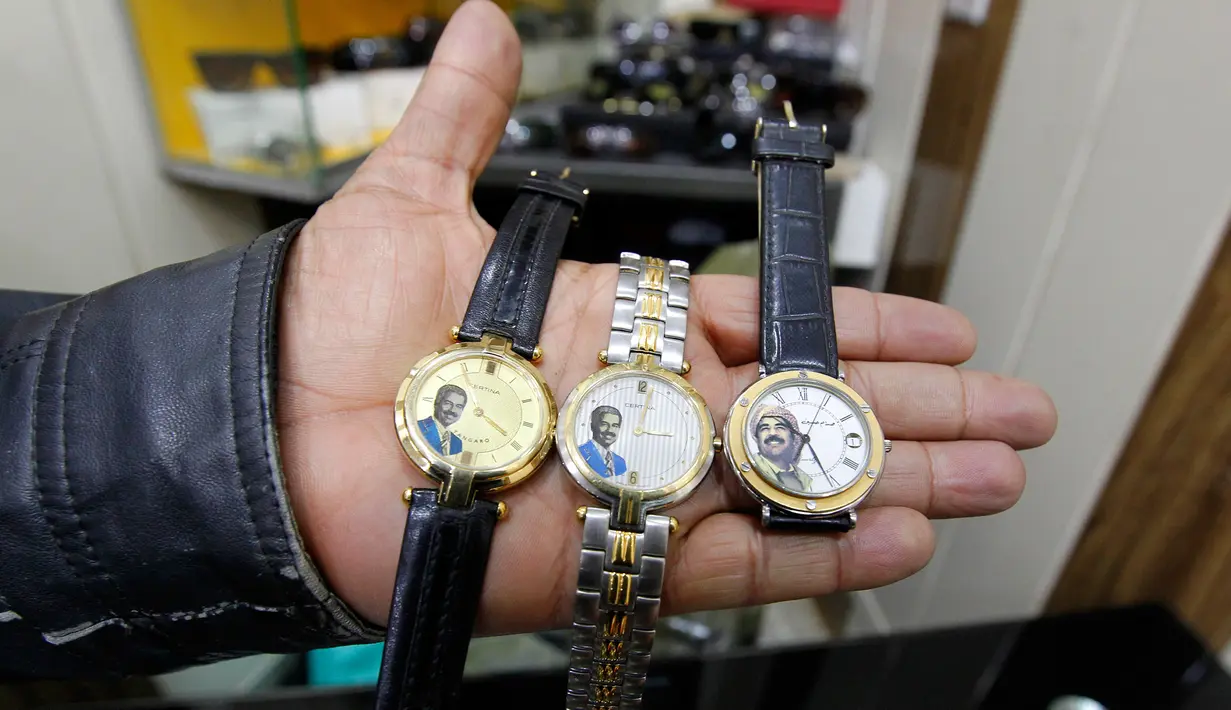 Seorang penjual menunjukan jam tangan yang bergambar mantan Presiden Irak, Saddam Hussein di Baghdad, Irak (28/12). Saddam Hussein adalah Presiden Irak yang menjabat sejak periode 16 Juli 1979 hingga 9 April 2003. (AFP/Sabah Arar)