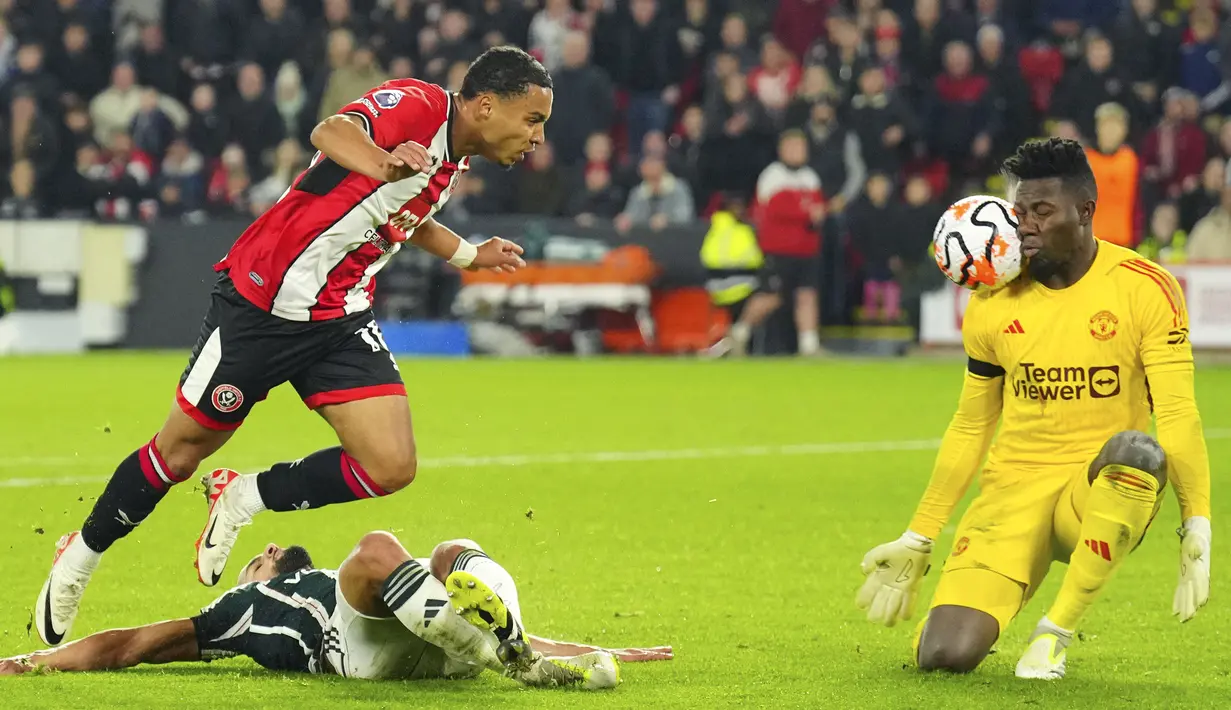Aksi penjaga gawang MU, Andre Onana (kanan), setelah berhasil mengagalkan tendangan pemain Sheffield United, Cameron Archer (kiri), dalam laga pekan ke-9 Premier League 2023/2024 yang berlangsung di Bramall Lane, Inggris, Minggu (22/10/2023). (AP Photo/Jon Super)