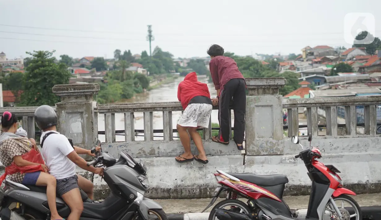 Pengendara sepeda motor mengamati banjir yang menggenangi kawasan Rawajati dari atas flyover di Jakarta Timur, Rabu (1/1/2020). Banjir yang berasal dari luapan Sungai Ciliwung itu menjadi daya tarik tersendiri bagi sebagian pemotor yang melintasi di flyover tersebut. (Liputan6.com/Immanuel Antonius)
