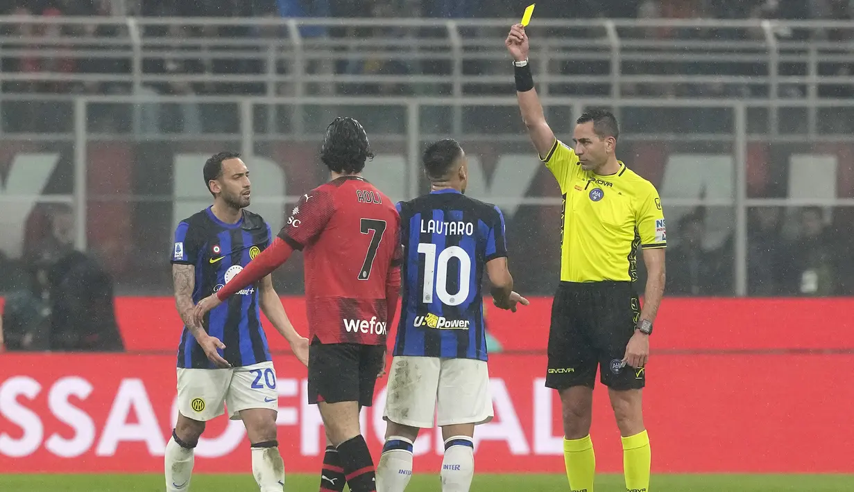 Wasit Andrea Colombo mengeluarkan kartu kuning kepada striker Inter Milan, Lautaro Martinez (kedua kanan) saat menghadapi AC Milan pada laga pekan ke-33 Serie A Liga Italia 2023/2024 di San Siro Stadium, Milan, Senin (22/4/2024). (AP Photo/Luca Bruno)