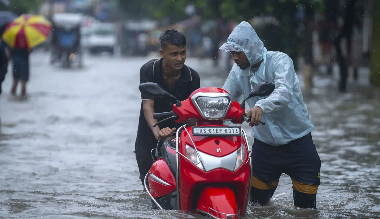 Anak laki-laki mendorong skuter melewati jalan yang banjir saat hujan deras di Guwahati, negara bagian Assam, India, Kamis (16/6/2022). Pemerintah Assam telah memerintahkan penutupan semua institusi pendidikan di Guwahati karena peringatan siaga merah untuk hujan lebat. (AP Photo/Anupam Nath)