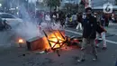 Seorang anak muda melintas di dekat kobaran api di kawasan Gondangdia, Jakarta, Kamis (8/10/2020). Aksi anarkis massa dilakukan saat berunjuk rasa menentang disahkan Omnibus Law UU Cipta Kerja. (Liputan6.com/Helmi Fithriansyah)