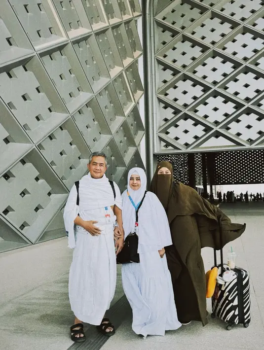 Awkarin tampil manis mengenakan gamis dan hijab cadar bernuansa kehijauan, bersama kedua orang tuanya yang mengenakan outfit Umroh serba putih. [Foto: Instagram/narinkovilda]