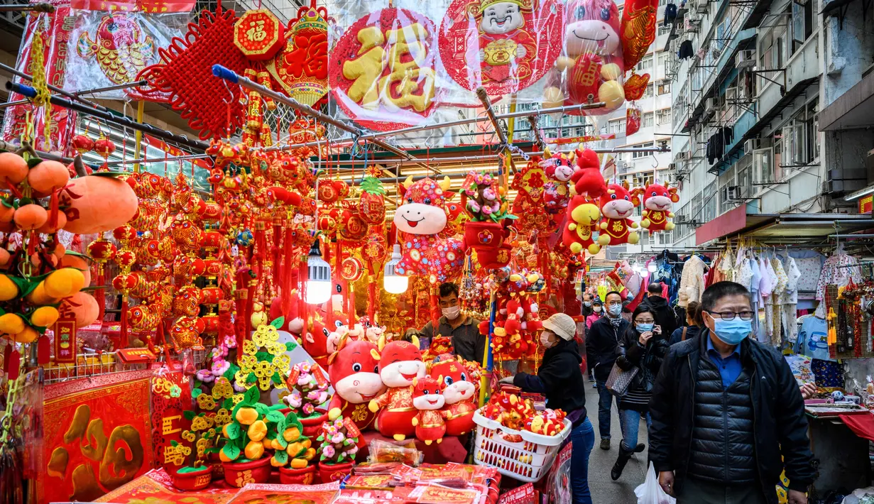 Pejalan kaki berjalan melewati kios yang menjual dekorasi di Hong Kong (14/1/2021). Menjelang Tahun Baru Imlek, tahun ini menandai Tahun Sapi, yang jatuh pada 12 Februari. (AFP/Anthony Wallace)