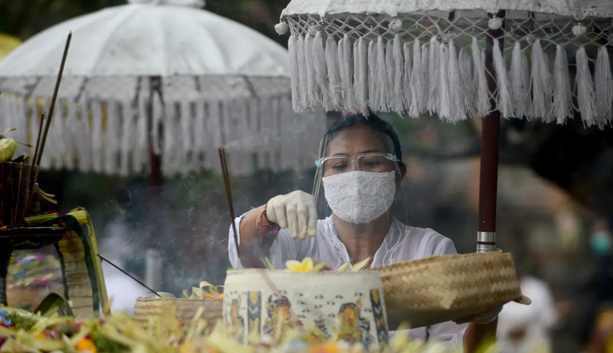 Seorang wanita hindu menyiapkan sesaji untuk berdoa dalam rangka merayakan festival keagamaan Galungan di Pura Jagat Natha di Denpasar, di pulau Bali (16/9/2020). Galungan dirayakan umat Hindu di Bali sebagai hari kemenangan Dharma (Kebaikan) melawan Adharma (Keburukan). (AFP Photo/Sonny Tumbelaka)