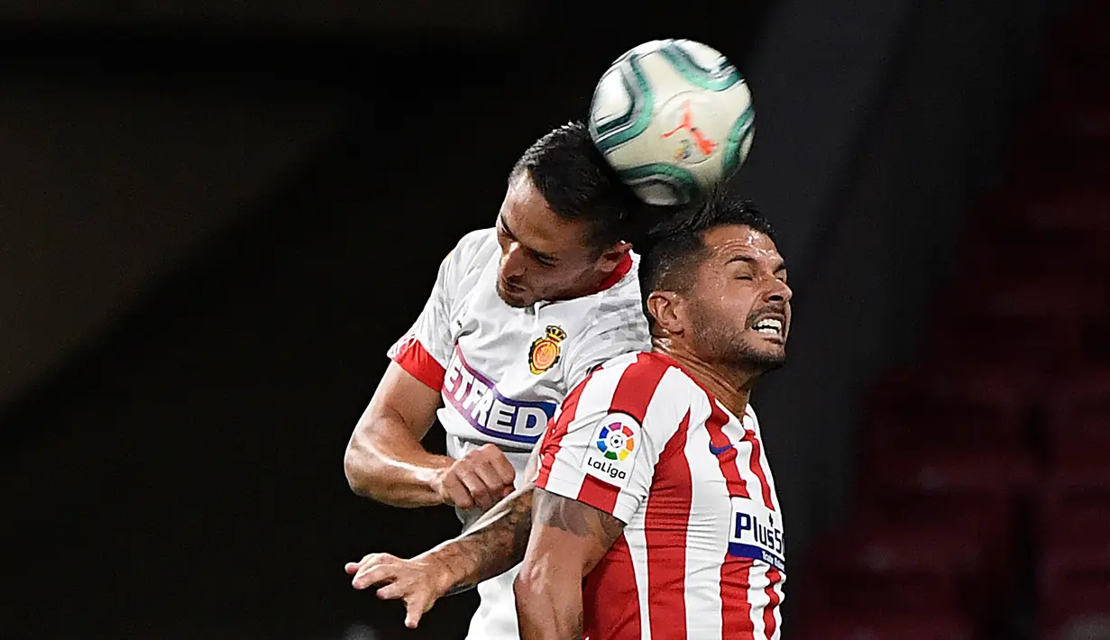 Gelandang Atletico Madrid, Vitolo, berebut bola atas dengan bek Real Mallorca, Antonio Raillo, pada laga lanjutan La Liga di Wanda Metropolitano, Sabtu (4/7/2020) dini hari WIB. Atletico Madrid menang 3-0 atas Mallorca. (AFP/Pierre-Philippe Marcou)