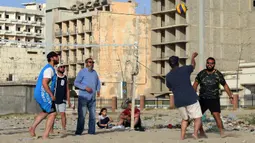 Orang-orang bermain voli pantai sembari menunggu waktu berbuka puasa selama bulan suci Ramadan, meskipun lockdown karena pandemi COVID-19, di ibu kota Tripoli, Libya pada Jumat (8/5/2020). (Photo by Mahmud TURKIA / AFP)