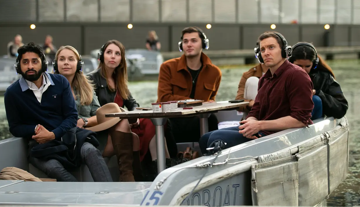 Orang-orang duduk di perahu menonton film pada layar lebar saat pratinjau bioskop apung di Merchant Square di Kanal Regent, London, Rabu (1/9/2020). Bioskop Openaireini itu memberi dua pilihan tempat duduk kepada penonton, yakni duduk di perahu atau di kursi di tepi kanal. (ISABEL INFANTES/AFP)