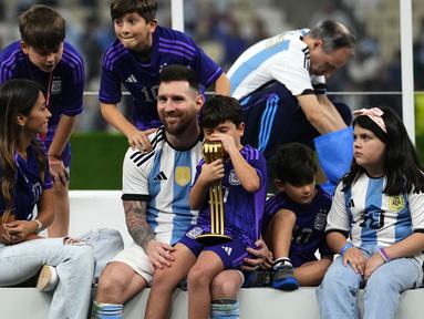 Pemain Argentina, Lionel Messi merayakan kemenangan timnya di Piala Dunia 2022 bersama keluarganya setelah mengalahkan Prancis pada laga final yang berlangsung di Lusail Stadium, Qatar, Minggu (18/12/2022). Albiceleste menang 4-2 atas Prancis di babak penalti. (AP Photo/Manu Fernandez)