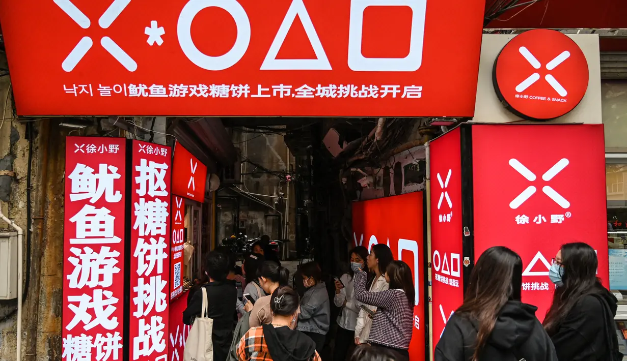 Pelanggan menunggu di toko kecil untuk dalgona, permen gula renyah yang ditampilkan dalam serial Netflix Squid Game, di Shanghai pada 12 Oktober 2021. Meski Netflix diblokir pemerintah China, tetapi serial Netflix Squid Game sukses meraih popularitas di 'Negeri Tirai Bambu' itu. (Hector RETAMAL/AFP)