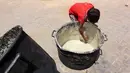 Seorang anak laki-laki Palestina mengorek sisa-sisa sup kacang miju-miju yang tersisa di dalam panci, di depan titik distribusi makanan di kamp pengungsian dekat pelabuhan Kota Gaza pada 22 Mei 2025. (Omar AL-QATTAA/AFP)