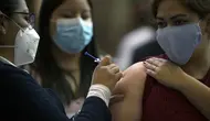 Seorang wanita muda menerima dosis pertama vaksin AstraZeneca di Mexico City, saat Meksiko menghadapi gelombang ketiga COVID-19, Selasa (10/8/2021). Hampir seperempat dari negara Meksiko berada dalam kondisi siaga merah karena infeksi Covid-19 naik ke level tertinggi. (ALFREDO ESTRELLA/AFP)