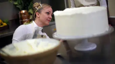 Pemilik Violet Bakery, Claire Ptak memberi sentuhan akhir pada kue pengantin Pangeran Harry dan Meghan Markle di dapur Istana Buckingham, London, Kamis (17/5). Harry dan Meghan akan menikah pada 19 Mei mendatang di Windsor Castle. (HANNAH MCKAY/POOL/AFP)