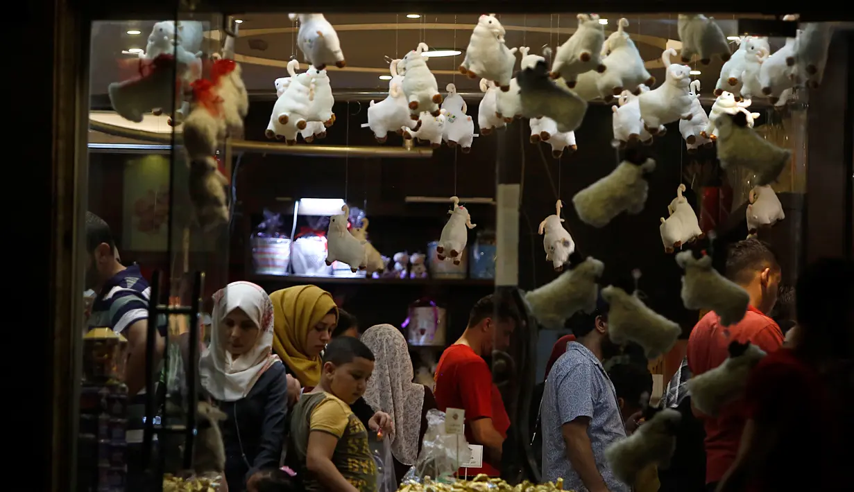 Keluarga Palestina membeli cokelat di sebuah toko yang dihiasi dengan boneka domba menjelang Hari Raya Idul Adha di kota Gaza pada Rabu (29/7/2020). (AP Photo/Hatem Moussa)