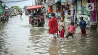 Anak-anak bermain saat banjir rob di Muara Angke, Jakarta, Jumat (25/11/2022). Badan Penanggulangan Bencana Daerah (BPBD) DKI Jakarta mengimbau agar warga di pesisir Jakarta mengantisipasi banjir pesisir atau rob selama 22-28 November 2022. (Liputan6.com/Faizal Fanani)