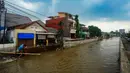 Pekerja membuat penahan tanggul kali sementara sepanjang 20 meter menggunakan papan, karung berisi pasir, dan rangka besi cor untuk mengurangi debit air yang masuk ke pemukiman warga. (merdeka.com/Arie Basuki)