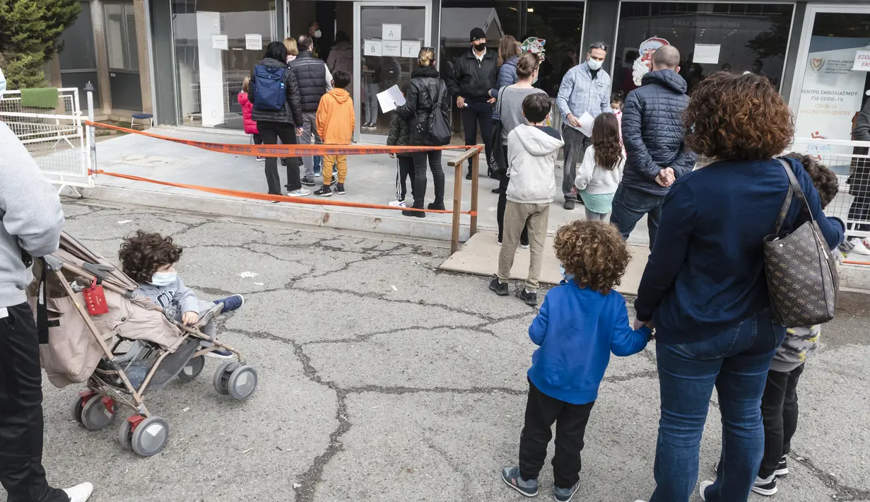 Orang tua mengantre di pusat vaksinasi bersama anak-anak mereka yang akan menerima vaksin covid-19 di ibu kota Siprus, Nicosia, Minggu (2/1/2022). Siprus memulai vaksinasi untuk anak-anak berusia antara 5 hingga 11 tahun, di tengah lonjakan tajam kasus virus corona. (Iakovos Hatzistavrou / AFP)