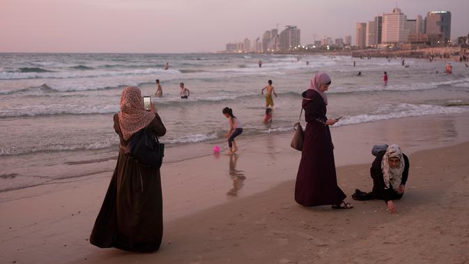 Muslim Palestina menghabiskan hari libur Lebaran di pantai Tel Aviv, Israel, 6 Juni 2019. Selama Idul Fitri, pemerintah Israel mengizinkan warga Palestina mengunjungi negaranya untuk menandai berakhirnya ibadah puasa Ramadan. (AP Photo/Oded Balilty)