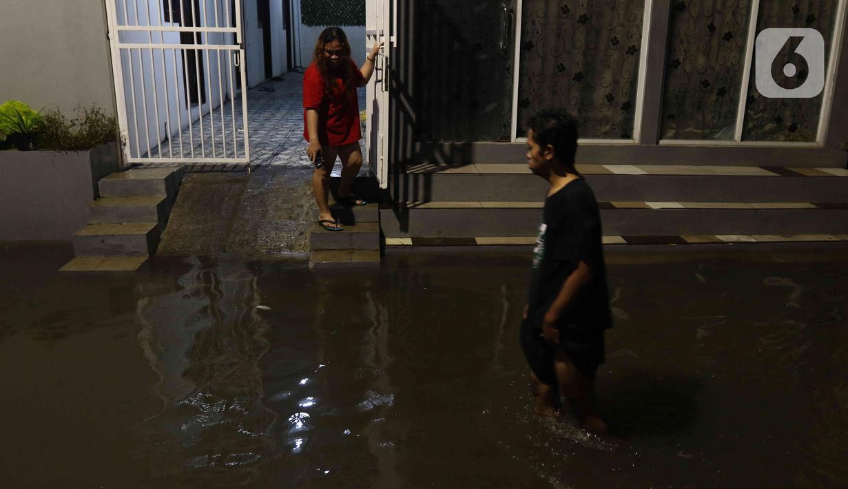 Warga sedang berjalan di tengah banjir yang melanda Jalan Bangka, Jakarta, Rabu (4/1/2023). Hujan deras yang terjadi pada Rabu sore membuat Kali Mampang meluap hingga menyebabkan banjir di kawasan tersebut dengan ketinggian bervariasi mulai dari 40 hingga 60 cm. (Liputan6.com/Herman Zakharia)