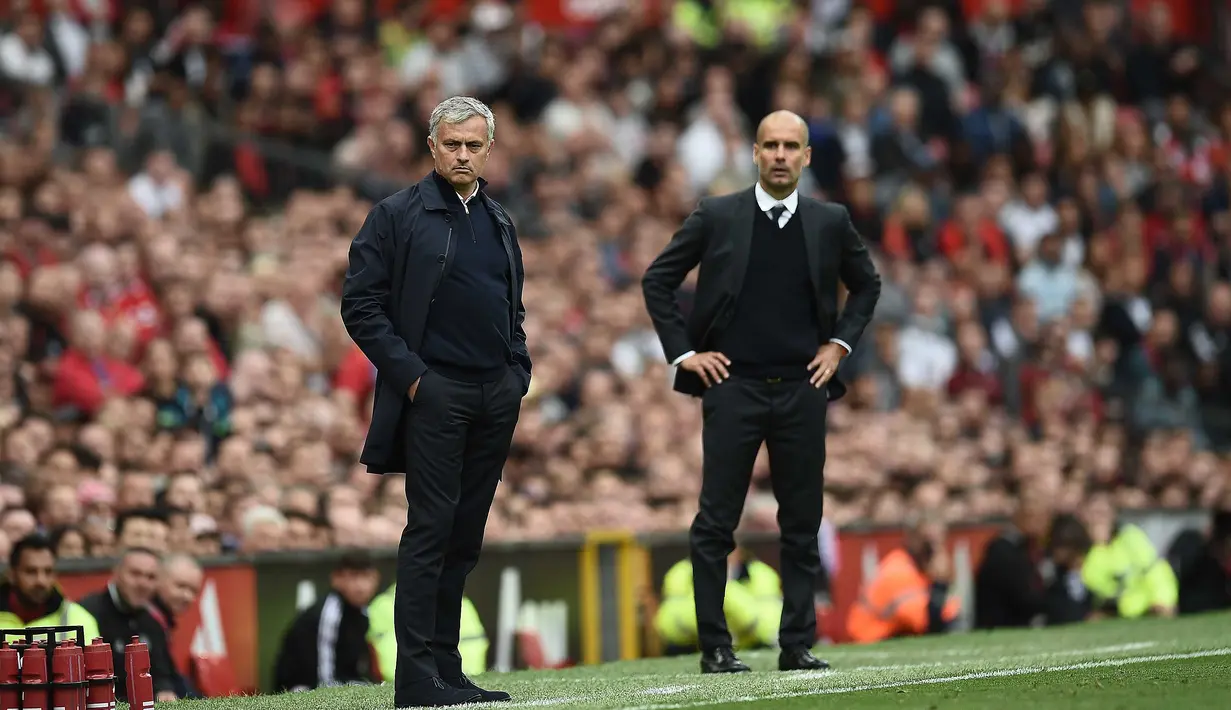 Aksi pelatih Manchester United, Jose Mourinho (kiri) dan pelatih  Manchester City, Pep Guardiola (R) saat menyaksikan anak asuhnya berlaga pada laga Premier League di Old Trafford, Manchester,  (10/9/2016). (AFP/Oli Scarff)