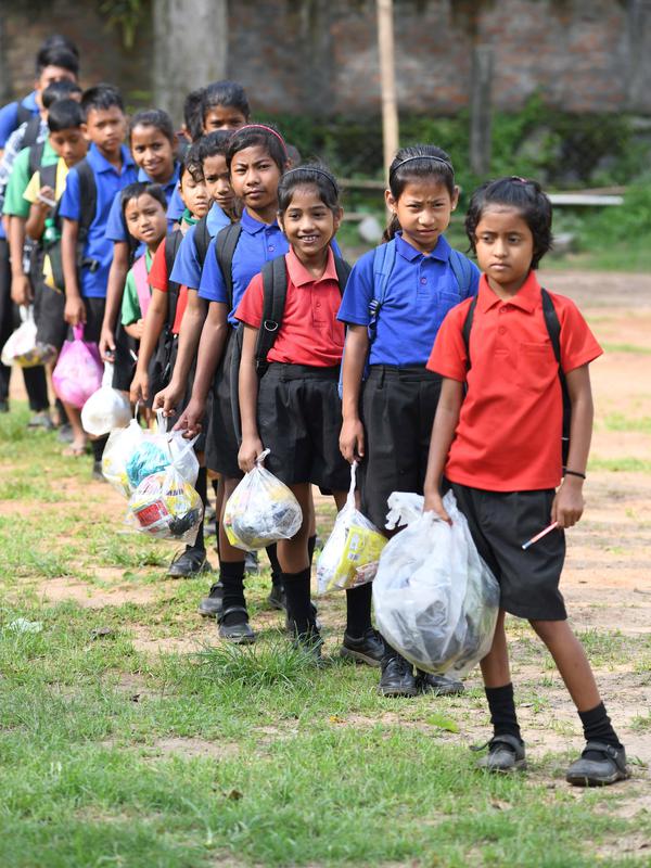 Gambar pada 20 Mei 2019, siswa India mengantre membawa tas plastik berisi sampah plastik di sekolah Forum Akshar di desa Pamohi, Guwahati. Sebanyak 110 murid sekolah ini harus membawa 20 item sampah plastik per minggu yang dikumpulkan dari rumah atau area sekitar mereka. (Biju BORO/AFP)