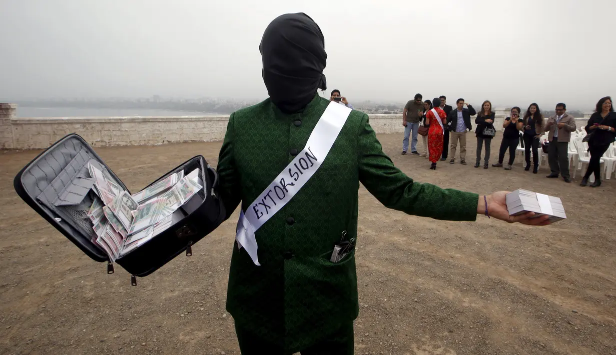 Pria membawa koper berisi uang selama melakukan tetrikal dalam partisipasi mengungkap korupsi di Lima,Peru, (12/11/2015). Acara diselenggarkan oleh organisasi non -pemerintah yang ingin menciptakan kesadaran tentang korupsi. (REUTERS/Mariana Bazo)
