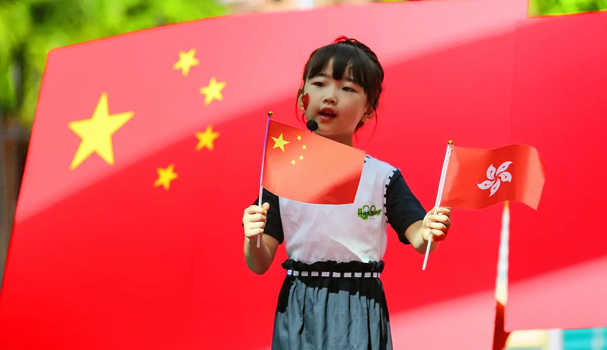 Seorang anak memperkenalkan bendera China dan Hong Kong kepada teman-temannya jelang peringatan penyerahan Hong Kong dari Inggris ke China di taman kanak-kanak di Shenzhen, Guangdong, China, Selasa (30/6/2020). Hong Kong menandai 23 tahun penyerahan dari Inggris ke Cina pada 1 Juli. (STR/AFP)