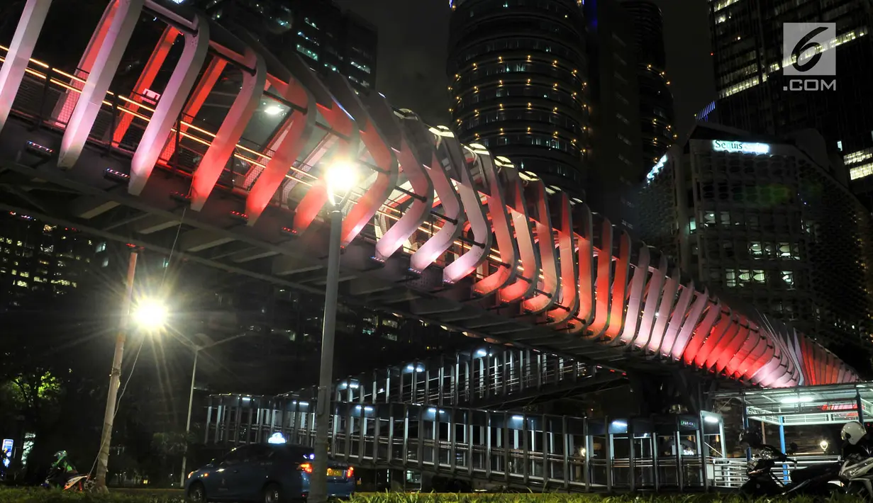 Kendaraan melintas di bawah jembatan penyeberangan orang (JPO) Gelora Bung Karno (GBK), Jakarta, Senin (25/2). JPO GBK memiliki keunikan dalam segi arsitektur dan keindahan gemerlap lampu pada malam hari. (Merdeka.com/Iqbal S Nugroho)