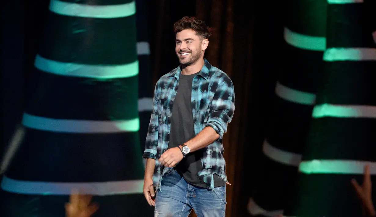 Aktor Zac Efron naik ke atas panggung untuk menerima penghargaan pada acara Teen Choice Awards di California, 12 Agustus 2018.  Mengenakan kemeja serta celana denim, Zac Efron kembali memancarkan pesona ketampanannya. (Chris Pizzello/Invision/AP)