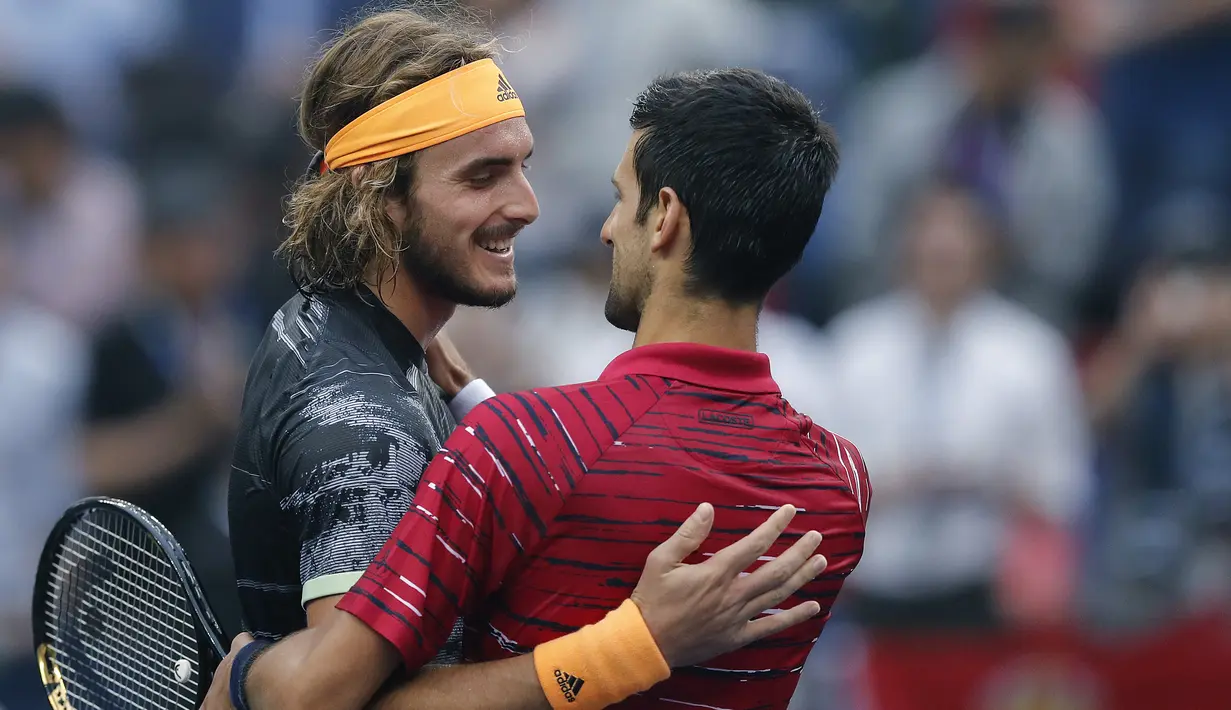 Petenis Yunani, Stefanos Tsitsipas memeluk Novak Djokovic dari Serbia setelah pertandingan perempat final tunggal putra tenis Shanghai Masters di Qizhong Forest Sports City Tennis Center di Shanghai, China (11/10/2019). Tsitsipas menang 3-6, 7-5, 6-3 atas Djokovic. (AP Photo/Andy Wong)