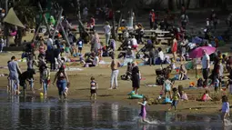 Orang-orang menikmati cuaca hangat di Ruislip Lido di London, Selasa (30/3/2021).  Suhu di beberapa bagian Inggris diperkirakan akan lebih hangat secara signifikan minggu ini karena keluarga dan teman berkumpul kembali dan kegiatan olahraga luar ruangan diizinkan untuk dilanjutkan di Inggris. (AP Ph