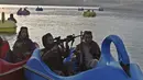 Sejumlah pasukan Taliban saat menaiki perahu kayuh di Danau Qargha di sebuah pekan raya di Kabul barat (28/9/2021). Sambil membawa senjata laras panjang sambil berjaga, mereka mengayuh perahu bebek memutari danau. (AFP/Wakil Kohsar)